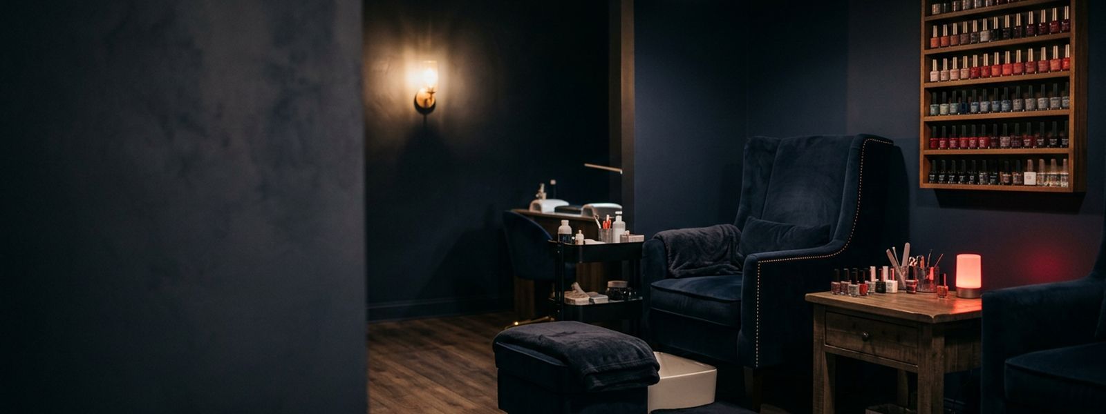 A nail salon station with a polish wall and pedicure chair under warm light