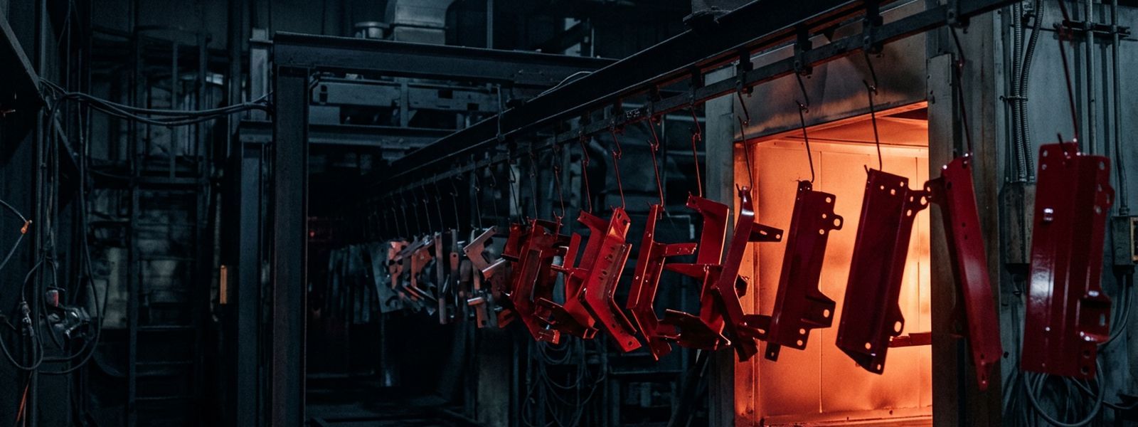 Coated parts hanging on the line as they enter the curing oven